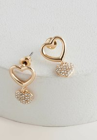 Aranyszínű fém fülbevalók, szív alakúak, lógó szív charm-mal díszítve, apró, átlátszó rhinestone-okkal ékesítve.