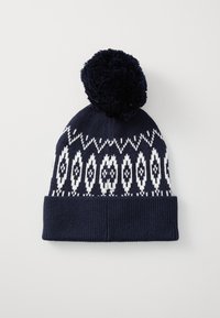 Bonnet en tricot bleu marine avec un motif géométrique blanc, featuring un grand pompon duveteux sur le dessus et un ourlet côtelé à la base.
