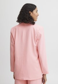 Lyserød blazer med lange ærmer, glat tekstur, enkelt rygsplit og notch-lapeller. Enkel, skræddersyet design med en ren silhuet.