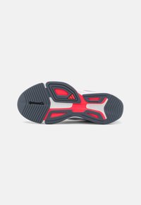 Shoe sole with a textured black rubber bottom, featuring red accents and a white midsole with gray components and visible Continental branding.