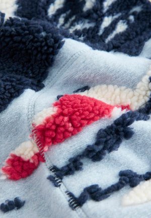 Bunt gemusterter Fleece-Stoff in Marineblau, Hellblau, Rot und Creme. Mit erhabener Struktur und weichem Finish.