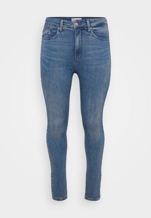 Jeans skinny in denim blu medio con una texture liscia, design a cinque tasche e chiusura con zip. Presenta un leggero sbiadimento e cuciture in tonalità.