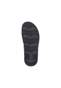 Semelle de chaussure en caoutchouc noir avec des motifs ondulés texturés et des rainures pour une meilleure adhérence. Présente un logo circulaire et un design de bout arrondi.