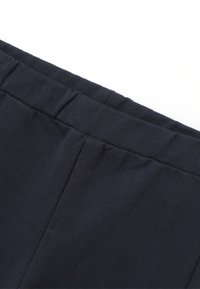 Cinturilla de tela azul marino con una textura suave, que presenta pliegues sutiles y una ancha banda elástica para mayor elasticidad y comodidad.