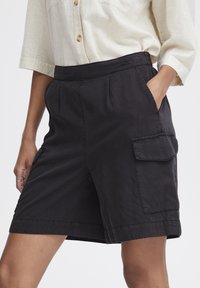 Shorts cargo noirs en tissu léger, avec des poches latérales, une coupe décontractée et une texture lisse et mate.
