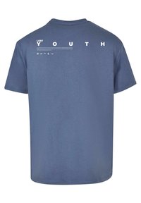 Blå bomull T-shirt med korta ärmar. Baksidan har stor vit text "LOST YOUTH" och horisontella linjemönster. Slät textur.