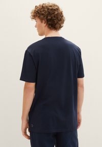 Tricou din bumbac de culoare albastru închis, cu mâneci scurte, de tip crew neckline și o croială lejeră, având un detaliu mic cu logo aproape de tiv.