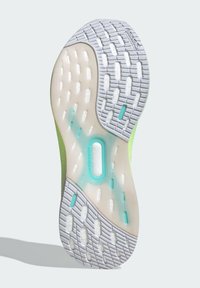 Podeszwa buta z białą gumową powierzchnią o fakturze z przezroczystymi akcentami. Zielony cholewka z niebieskim detalem systemu torsji.