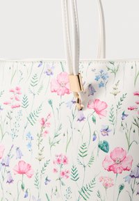 Blumen-Shopper mit einem weißen texturierten Hintergrund, der mit pinken und lila Blumen versehen ist. Goldene Hardware-Akzente und doppelte weiße Griffe.