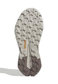 Tread of a shoe with a rubber sole featuring a dynamic pattern of protruding triangles in light gray and dark brown tones.