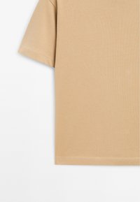Beige Baumwoll-T-Shirt mit kurzen Ärmeln, einem runden Halsausschnitt und einer glatten, gleichmäßigen Textur. Der Saum ist ordentlich genäht für Haltbarkeit.