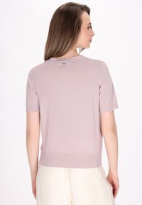 Maglione a maniche corte rosa chiaro con scollatura rotonda e orlo a costine. Tessuto morbido con una leggera lucentezza, caratterizzato da una piccola etichetta con logo sul retro.