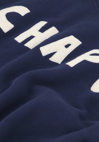 Felpa marina con caratteri bianchi in blocco in evidenza "CHAP" e un tessuto morbido e texture; presenta una vestibilità comoda e un collo a coste.
