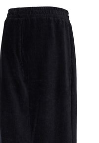 Pantalon en velours côtelé noir avec taille élastique, visible de la taille jusqu'à la partie supérieure de la cuisse.