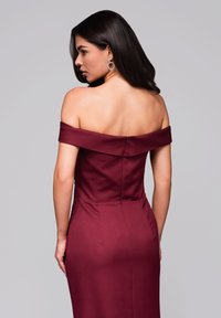 Burgundské šaty bez ramínek s přiléhavým živůtkem a zipem na zadní straně. Hladká tkanina s elegantní a štíhlou siluetou.