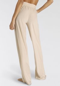 Beige, leichte, fließende Hose mit elastischem Bund, weitem Bein und glatter Textur, die einen lässigen Schnitt und minimale Details präsentiert.
