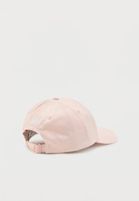 Ροζ ροδακινί ρυθμιζόμενο καπέλο του μπέιζμπολ με καμπύλη γείσο και μικρό λευκό λογότυπο στο πίσω μέρος, εμφανιζόμενο από οπίσθια γωνία σε λευκό φόντο.