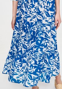 Blue and white floral pattern dress featuring a tiered design, lightweight fabric, and a ruffled hem.