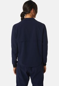 Marineblaue Jacke mit langen Ärmeln, ausgestattet mit einem Rückenpasse-Design. Glattes Material mit lockerer Passform. Die Bündchen haben einen kontrastierenden schwarzen Abschluss.
