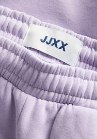 Lavendel joggerbukser med elastisk talje og indsamlet tekstur. Mærket siger "JJXX" i mørkeblå. Blødt bomuldsstof.