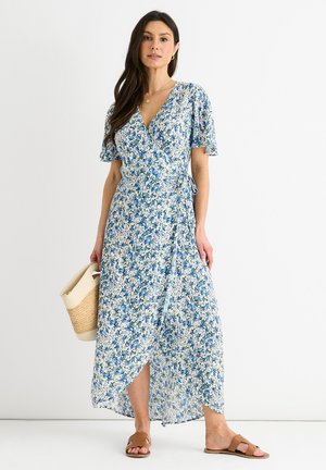Ärmelloses Blumenkleid in Hellblau mit kleinen, verstreuten blauen und grünen Blumen. Kurze Puffärmel und gebundenem Taillengürtel. Fließender Stoff.