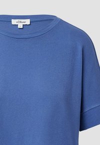 Niebieska bawełniana koszulka z okrągłym dekoltem, krótkimi rękawami i fakturowaną powierzchnią. Metka z napisem "s.Oliver" znajduje się przy kołnierzyku.
