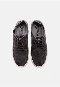 Szürke vászon sportcipők kerek orral, texturált felülettel és kontrasztos fehér gumitalppal. Fűzőzáras kialakítás és logó a talpbetéten.