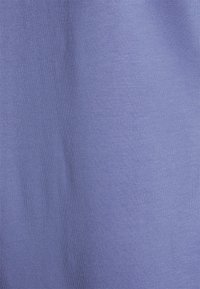 Tecido elástico de cor roxa clara exibindo uma textura lisa e consistente. Sem padrões ou acentos visíveis, com uma cor uniforme em todo o tecido.