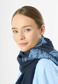 Écharpe bleu foncé enroulée autour du cou, ornée d'un motif texturé bleu clair, fabriquée dans un matériau doux avec un éclat subtil.