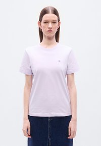 Ανοιχτό μωβ κοντομάνικο βαμβακερό T-shirt με στρογγυλή λαιμόκοψη· διαθέτει μικρό, ομοιόχρωμο λογότυπο CK στο αριστερό στήθος.