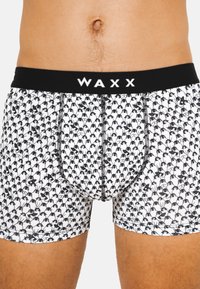 Boxers ajustés pour hommes en tissu blanc avec un motif de pingouins noirs répété, dotés d'une ceinture élastique noire portant l'inscription "WAXX."
