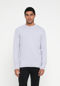 Pulover cu textura, de culoare lavandă deschisă, cu decolteu rotund și mâneci lungi, cu guler cu dungi, asortat cu pantaloni negri. Design simplu și minimalist.