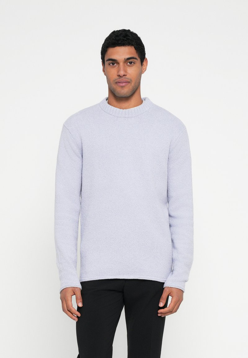 Pulover cu textura, de culoare lavandă deschisă, cu decolteu rotund și mâneci lungi, cu guler cu dungi, asortat cu pantaloni negri. Design simplu și minimalist.