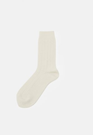 Chaussettes arrivant au genou en beige clair avec un motif de côtes verticales. Matière douce et extensible avec un bout arrondi et un talon renforcé.
