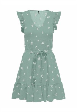 Robe sans manches vert sauge avec petit imprimé floral blanc, encolure en V, bords de manches à volants, ceinture à la taille et ourlet à volants superposés.