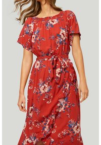 Vestido rojo de flores con mangas cortas, escote fruncido y cinta en la cintura. Presenta un dobladillo con volantes y patrones florales en azul y blanco. Textura de tela suave.