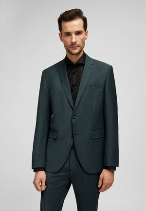 Dunkelblauer Anzugjacke mit strukturierter Oberfläche, ausgestattet mit einem Knopfverschluss, Reverskragen und zwei vorderen Taschen, kombiniert mit einem schwarzen Hemd.