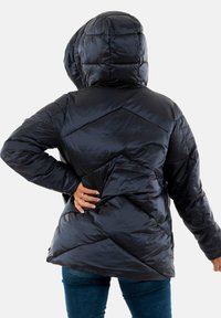 Chaqueta acolchada negra con capucha, de mangas largas y con costuras diagonales. El material es brillante y elegante, y presenta una silueta ajustada.