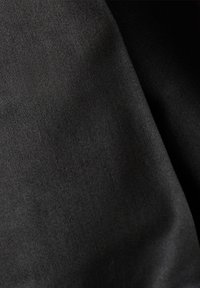 Tissu noir avec une surface lisse légèrement texturée et des plis subtils créant de douces ombres.