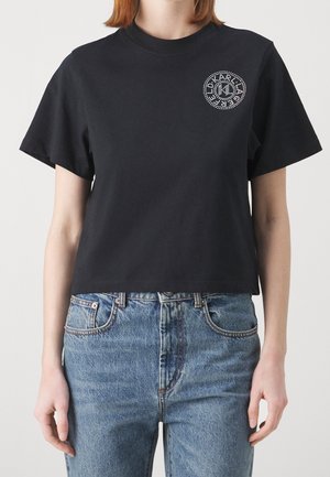 T-shirt noir raccourci en coton, avec un col rond et des manches courtes. Le devant présente un motif circulaire en strass.