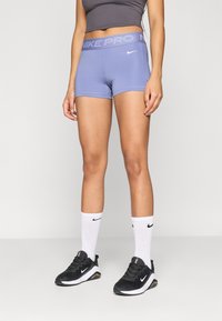 Šviesiai mėlyni Nike Pro šortai, pagaminti iš tamprios medžiagos. Yra platus juosmens diržas su įspauduota ženklinimo ir akcento juostelėmis.