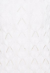 Biała dziana tkanina z wzorami diamentów, z teksturowanymi detalami i otwartymi ściegami, zapewniająca lekką i delikatną prezencję.