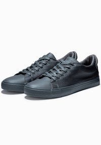 Grå sneakers med en slät läderskydd framtill och ovandel av mesh, med platta snören, vadderad krage och texturerad gummisula.