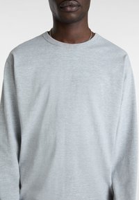 Jasnoszara, długosleeve T-shirt wykonany z miękkiej tkaniny. Posiada okrągły dekolt i minimalistyczny design bez widocznych wzorów czy akcentów.