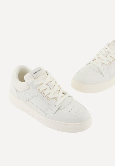 Sneakers bianchi con una tomaia in pelle liscia, dettagli in mesh, lacci piatti bianchi, punta perforata e una suola in gomma texturizzata.