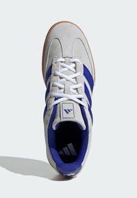 Gray suede sneaker with navy blue stripes, white laces, and a textured rubber sole. Features padded collar and logo on the heel.