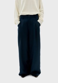 Pantaloni a gamba larga, di un blu navy scuro, con vita alta, pieghe, tasche laterali e chiusura con un bottone, realizzati in tessuto morbido.
