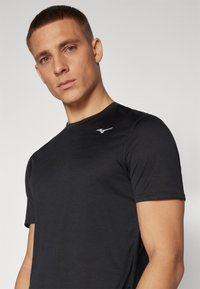Camiseta deportiva negra de manga corta, hecha de tejido suave, con un sutil logo en el pecho y un escote redondeado.