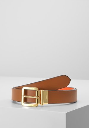Ceinture en cuir marron avec boucle rectangulaire dorée, présentée enroulée sur une surface blanche, avec une doublure intérieure orange.