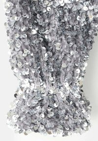 Tissu gris orné de paillettes argentées, créant une surface texturée et réfléchissante. Les paillettes sont densément disposées pour un effet scintillant.